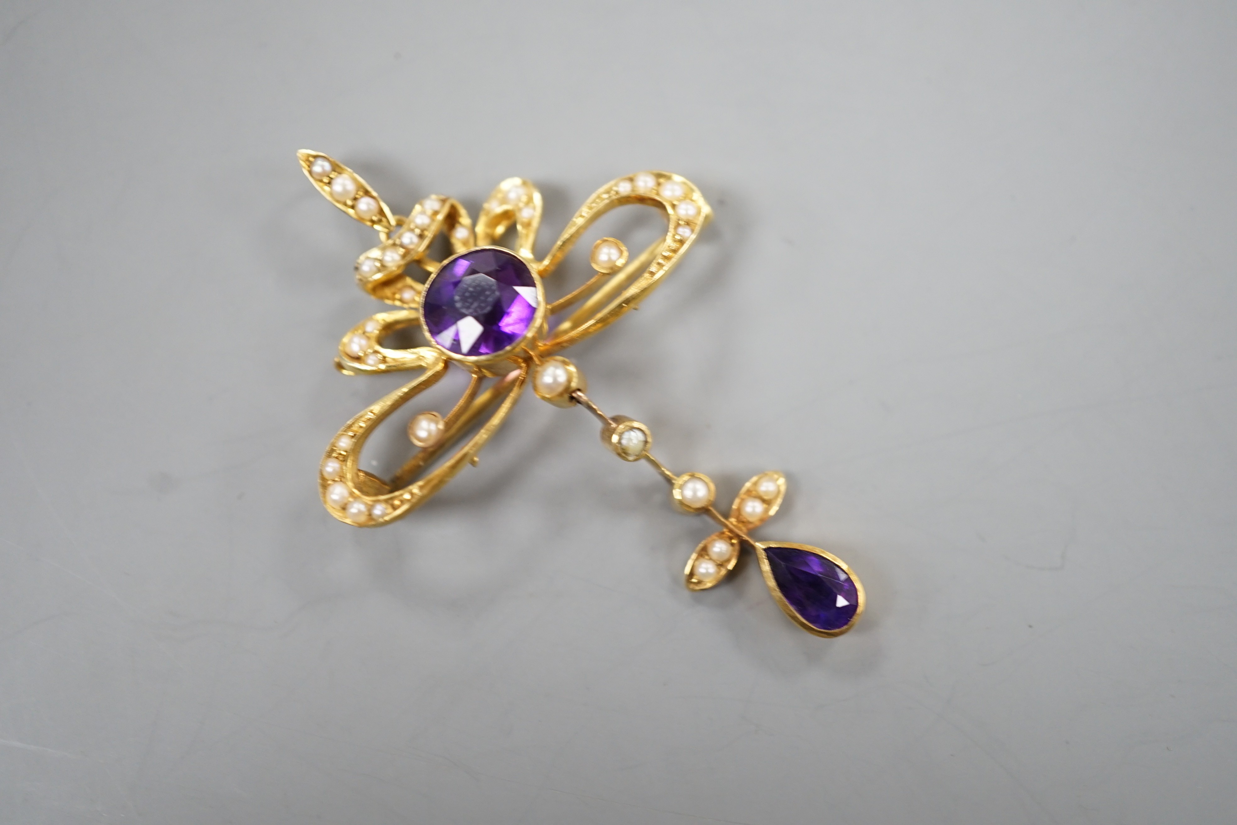 An Edwardian 15ct, amethyst and seed pearl set drop pendant brooch, overall 49mm, gross weight 5.3 grams.
